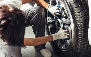 Person bringt einen Reifen an ein Auto an.