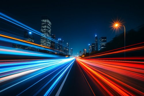 Langzeitbelichtung von Autoscheinwerfern auf nächtlicher Stadtautobahn – Lichtspuren in Blau und Rot.